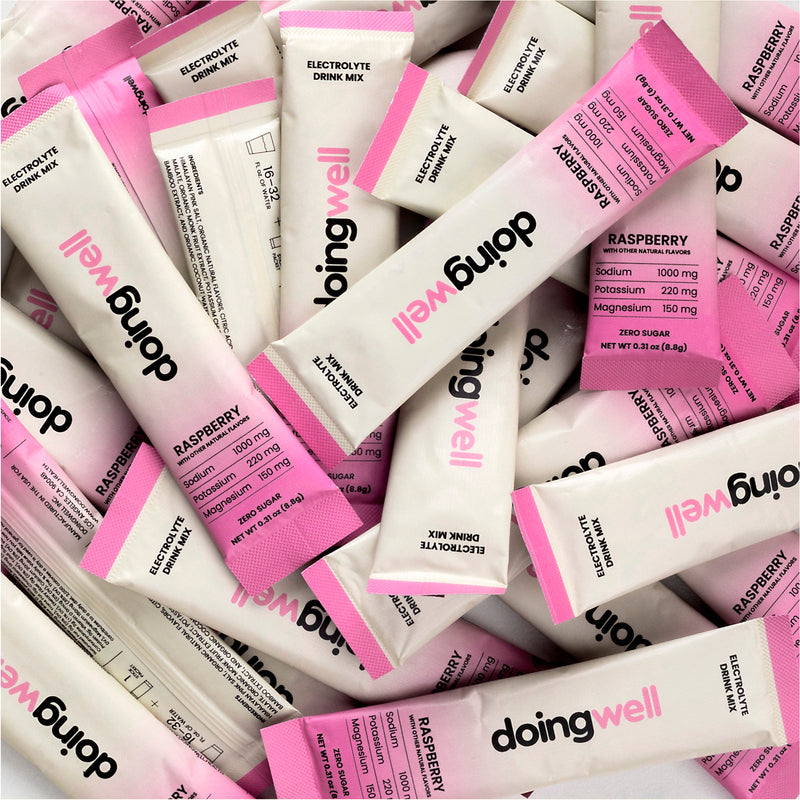 Pile of 'doing well' electrolyte drink mix packets with pink and white packaging.