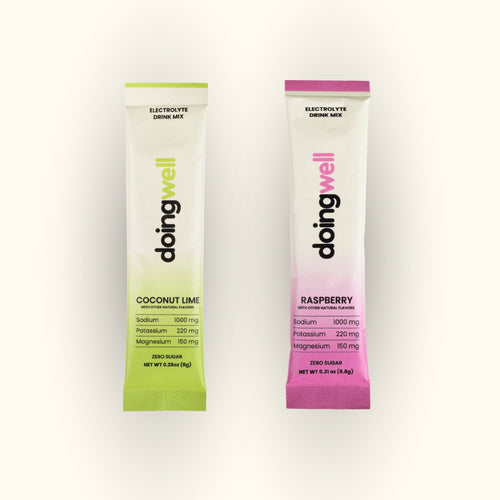 sampler packets of doing well electrolyte drink mix, one coconut lime and one raspberry, on a white background. High sodium electrolytes sample pack